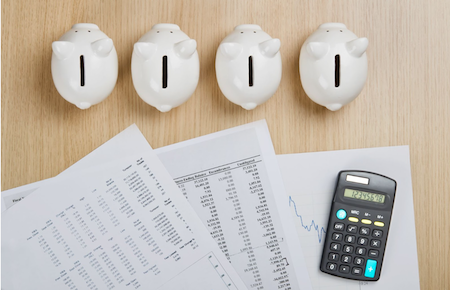 Piggybanks, calculator, and spreadsheets on a table